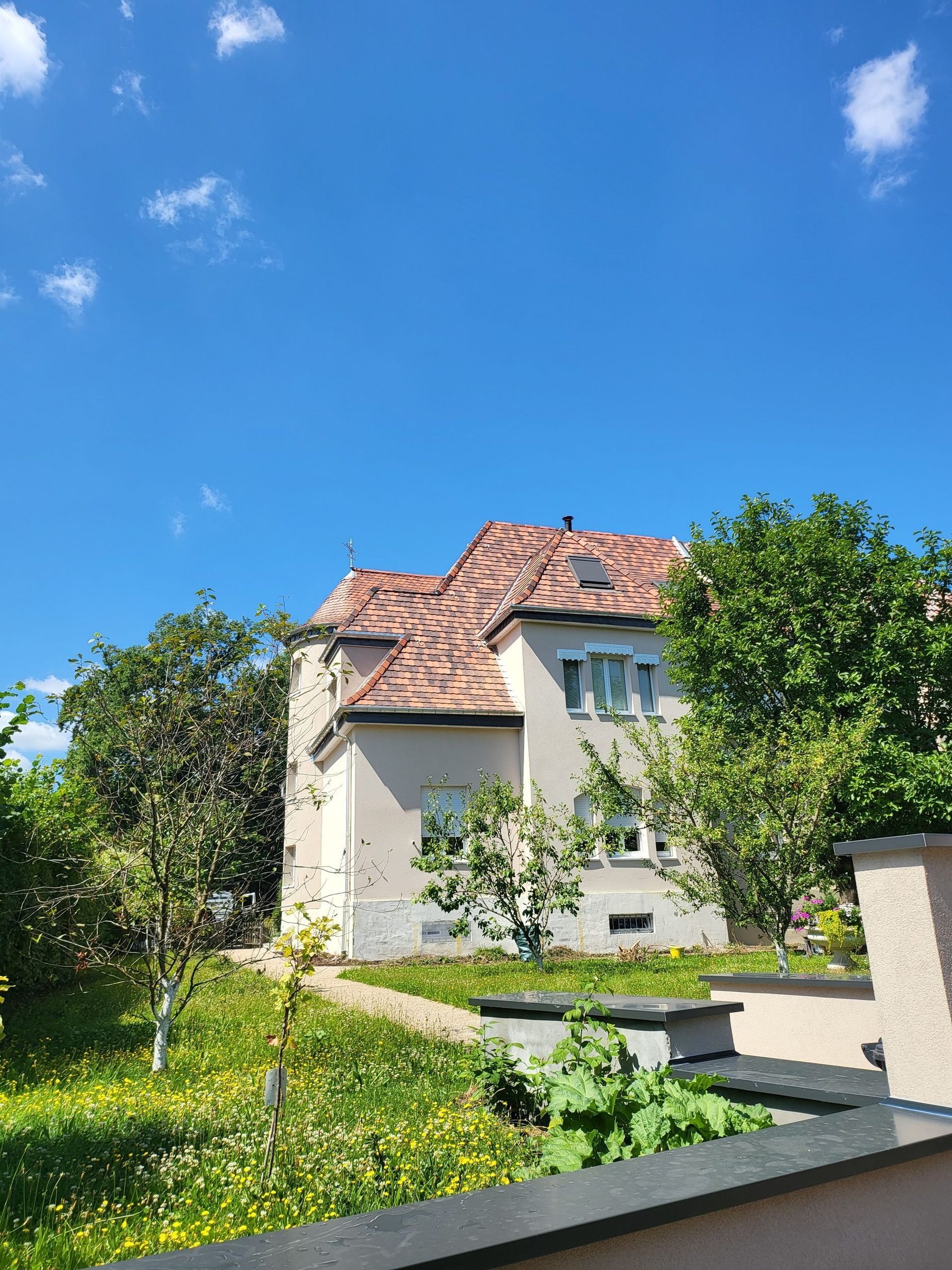 Maison bourgeoise à tourelle couverte de tuiles neuves sous un ciel bleu